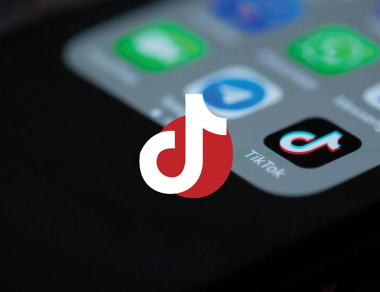 Photo of the TikTok logo overlayed on a photo of a phone.